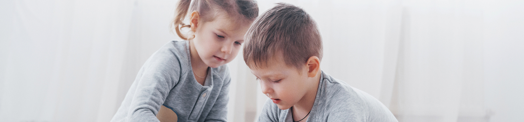 Dwoje dzieci w wieku 4 lat bawi się kolorowymi klockami od projektanta zabawek na podłodze w pokoju dziecięcym, ciesząc się razem z przedszkolnymi grami edukacyjnymi.