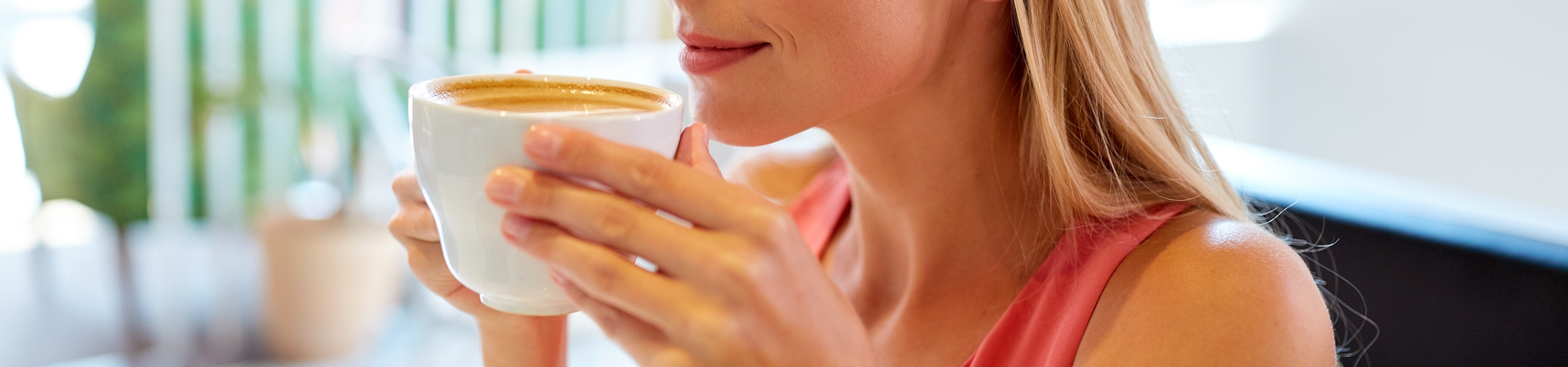 Kobieta w bluzce bez rękawów trzyma biały kubek Kobieta pije kawę